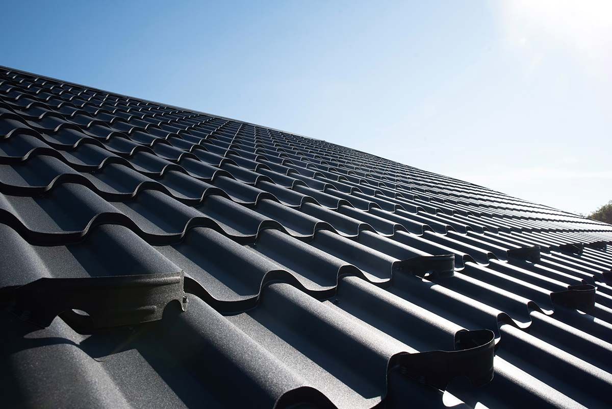 Black tiled roof against a clear blue sky, viewed from a low angle.