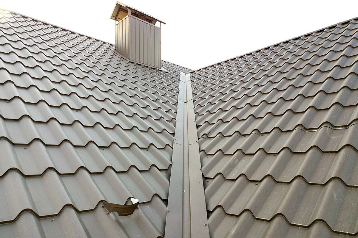 Gray metal tile roof with chimney and gutter.