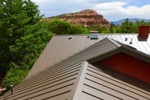 Brown metal roof with a view of a red rock mountain and green trees.