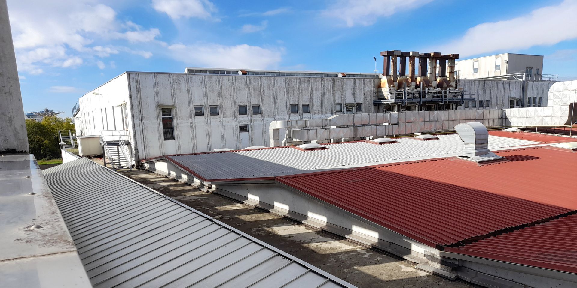 Exterior shot of a building with a red and gray roof under a blue sky.