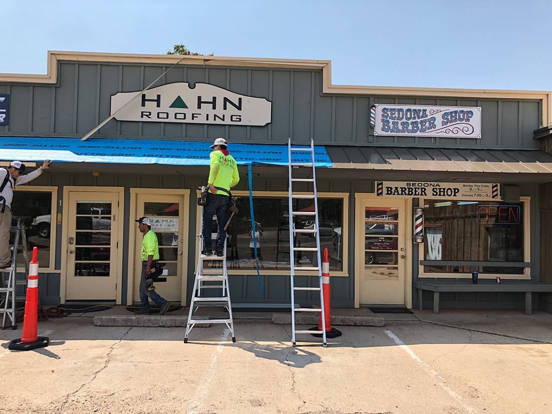 Workers on ladders installing or repairing a storefront awning in front of 