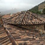 Clay tile roofs, overcast sky, mountain in background.