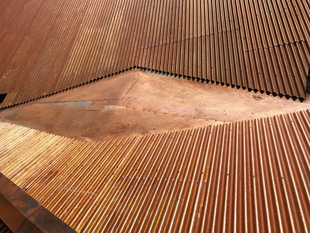 Close-up of a brown shingled roof with two skylights and a small vent.