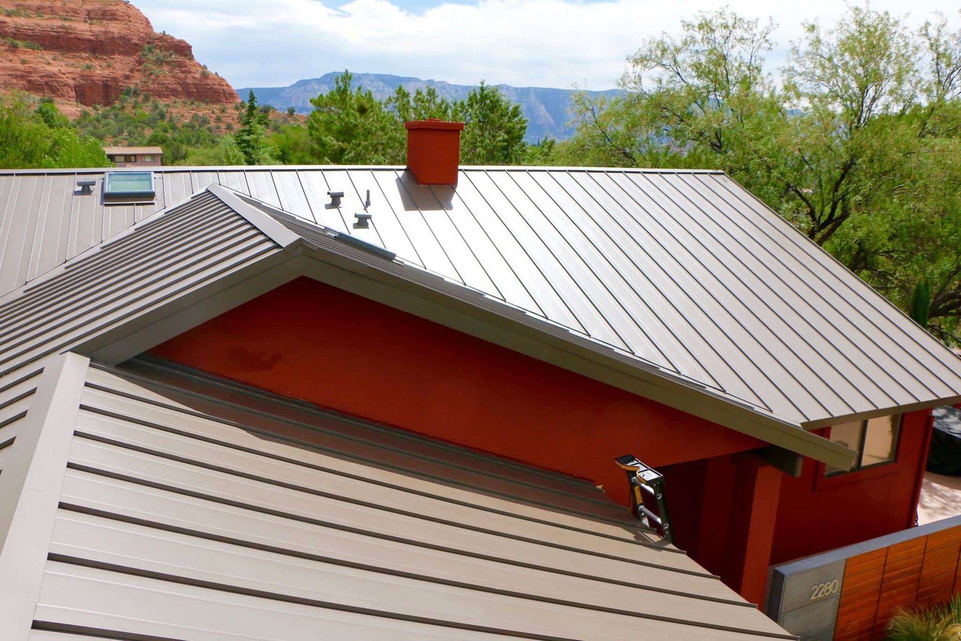 Brown metal roof with orange accent and red rock background.