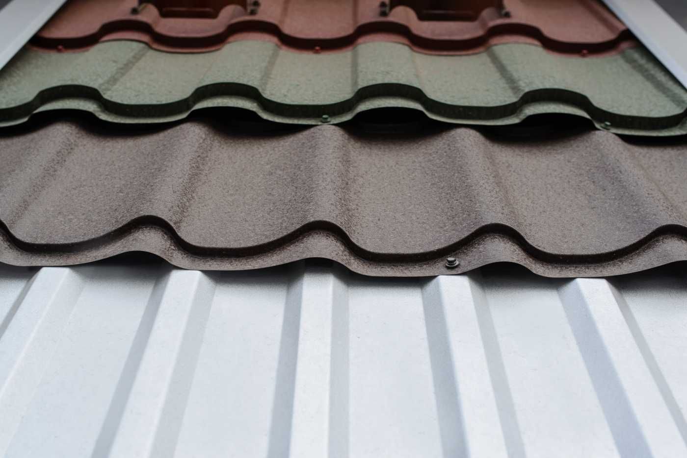 Samples of roofing materials: red, green, and tan textured tiles atop white corrugated metal.