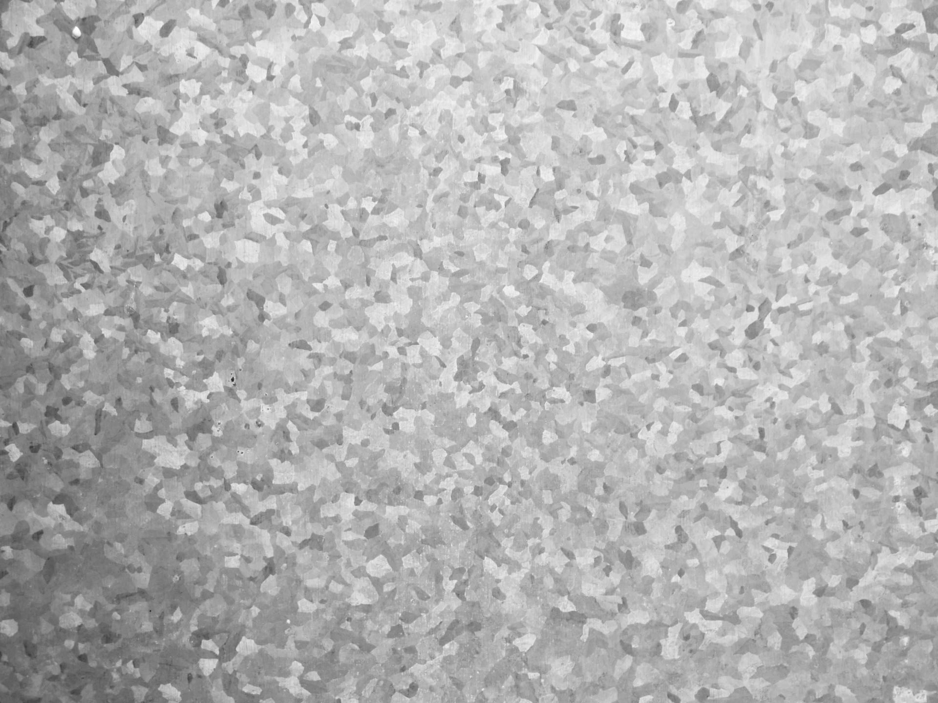 Close-up view of galvanized steel, showing a textured surface with crystalline patterns in shades of gray.