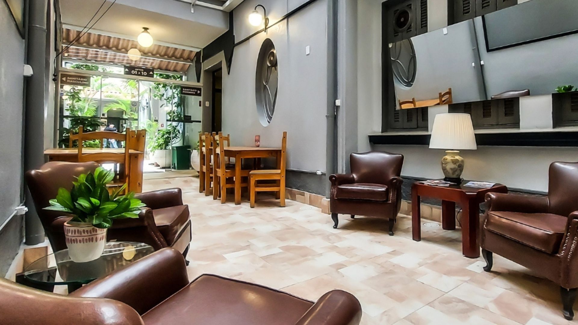Uma sala de estar com cadeiras, mesas e um abajur.