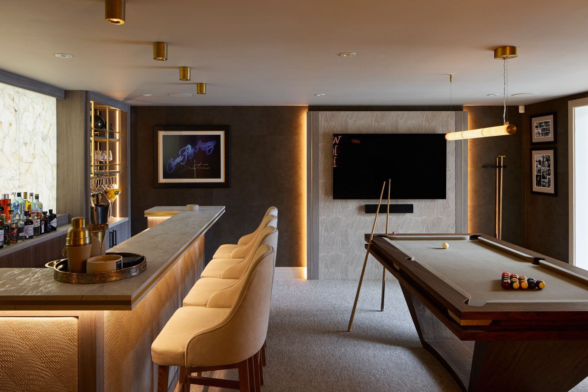 Modern game room with pool table, bar seating, wall TV, and warm pendant lighting
