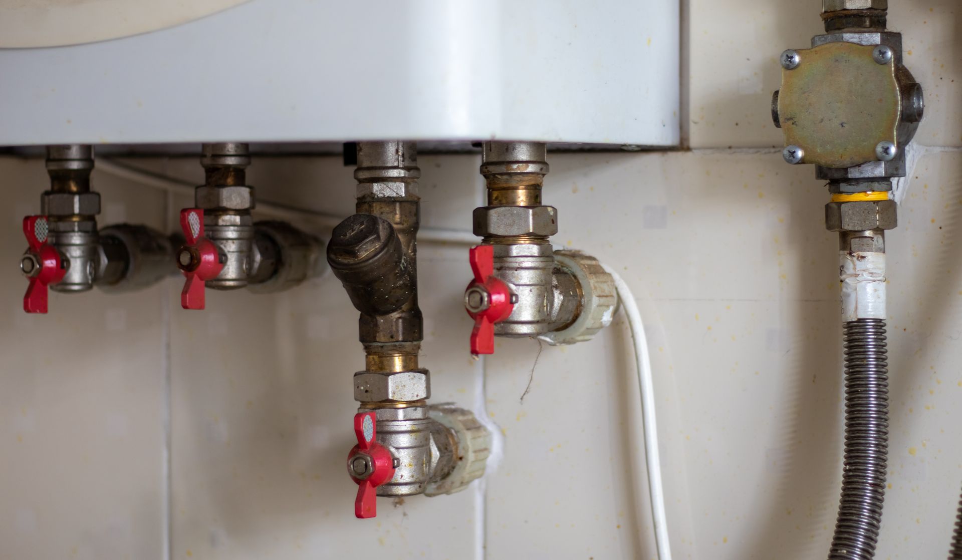 Pipes and Valves Connected to a Water Heater on a Tiled Wall — B&A Plumbing and Gas In Wauchope, NSW