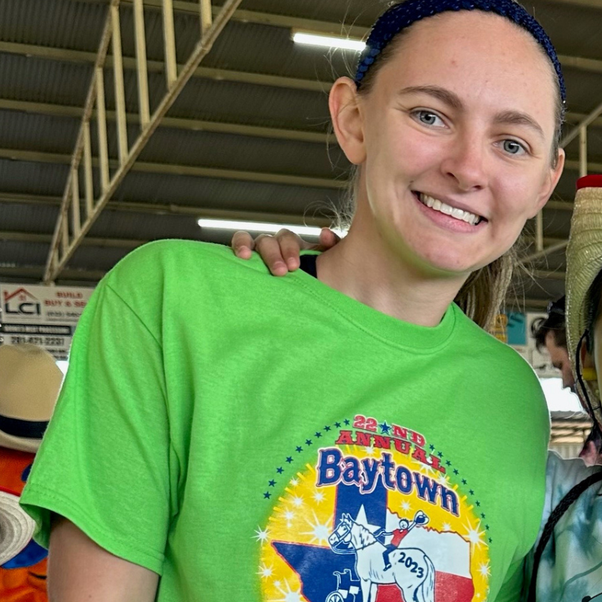 Smiling person in a bright green Baytown T-shirt at an indoor event