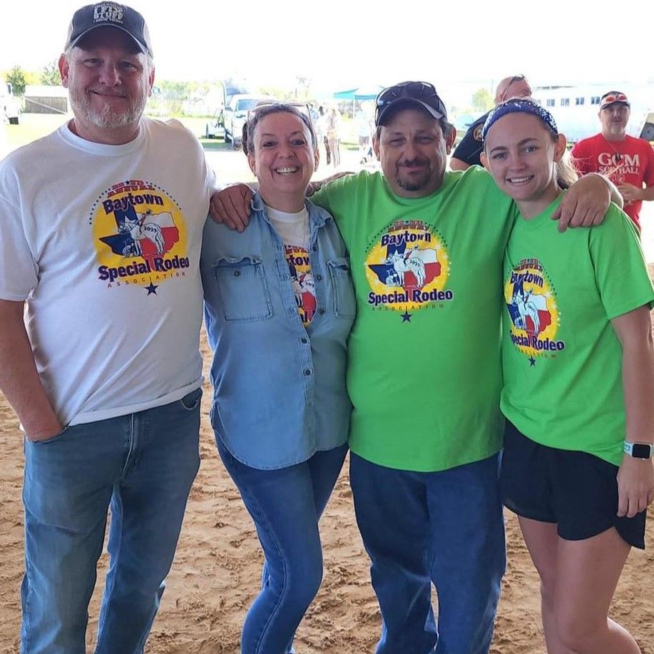 Four adults posing for a photo, all wearing shirts with the