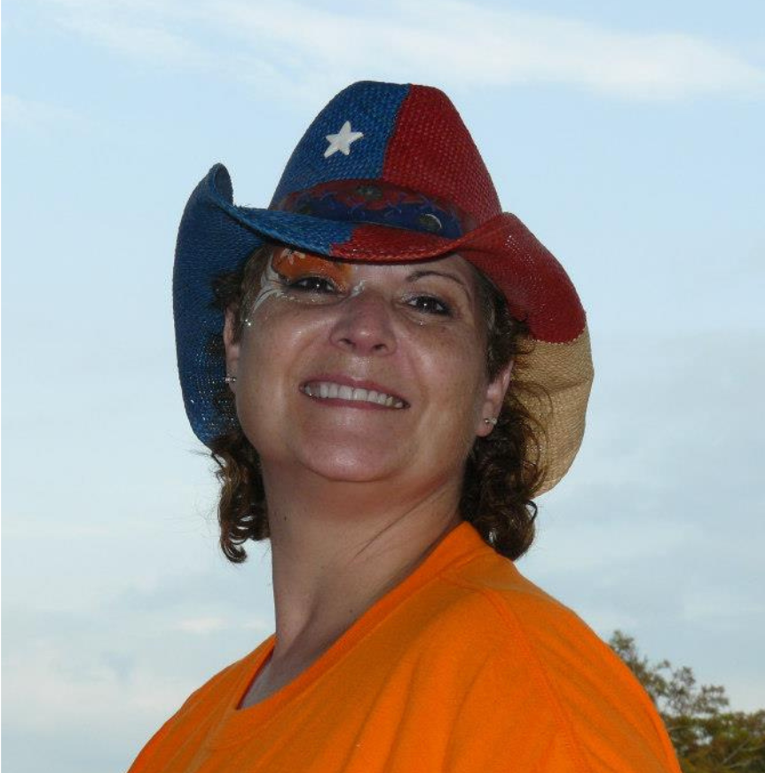Person smiling in a red, white, and blue cowboy hat against a blue sky