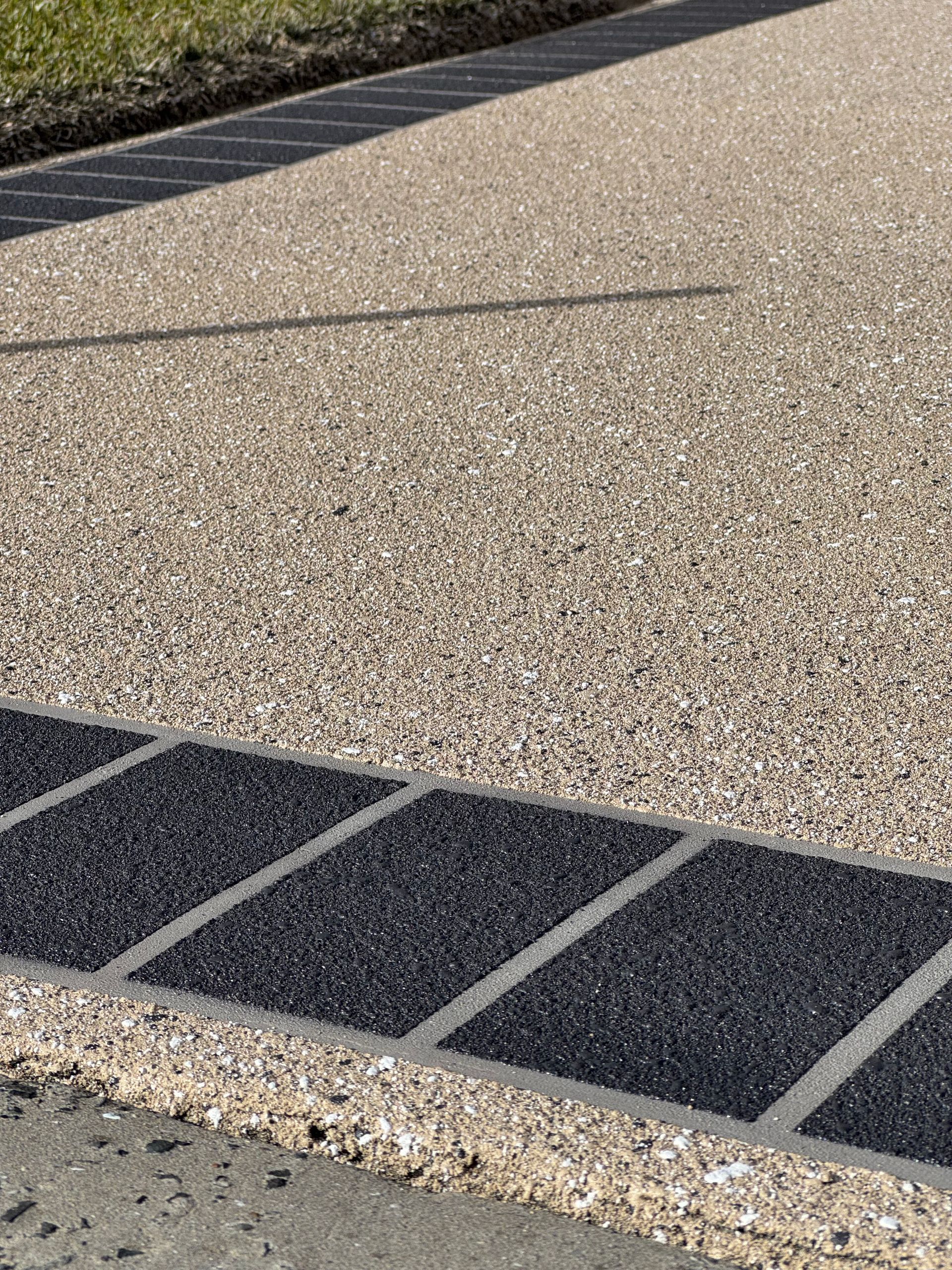 A gravel driveway with a black border and a lawn in the background — Illawarra Resurfacing Pty Ltd in Balgownie, NSW