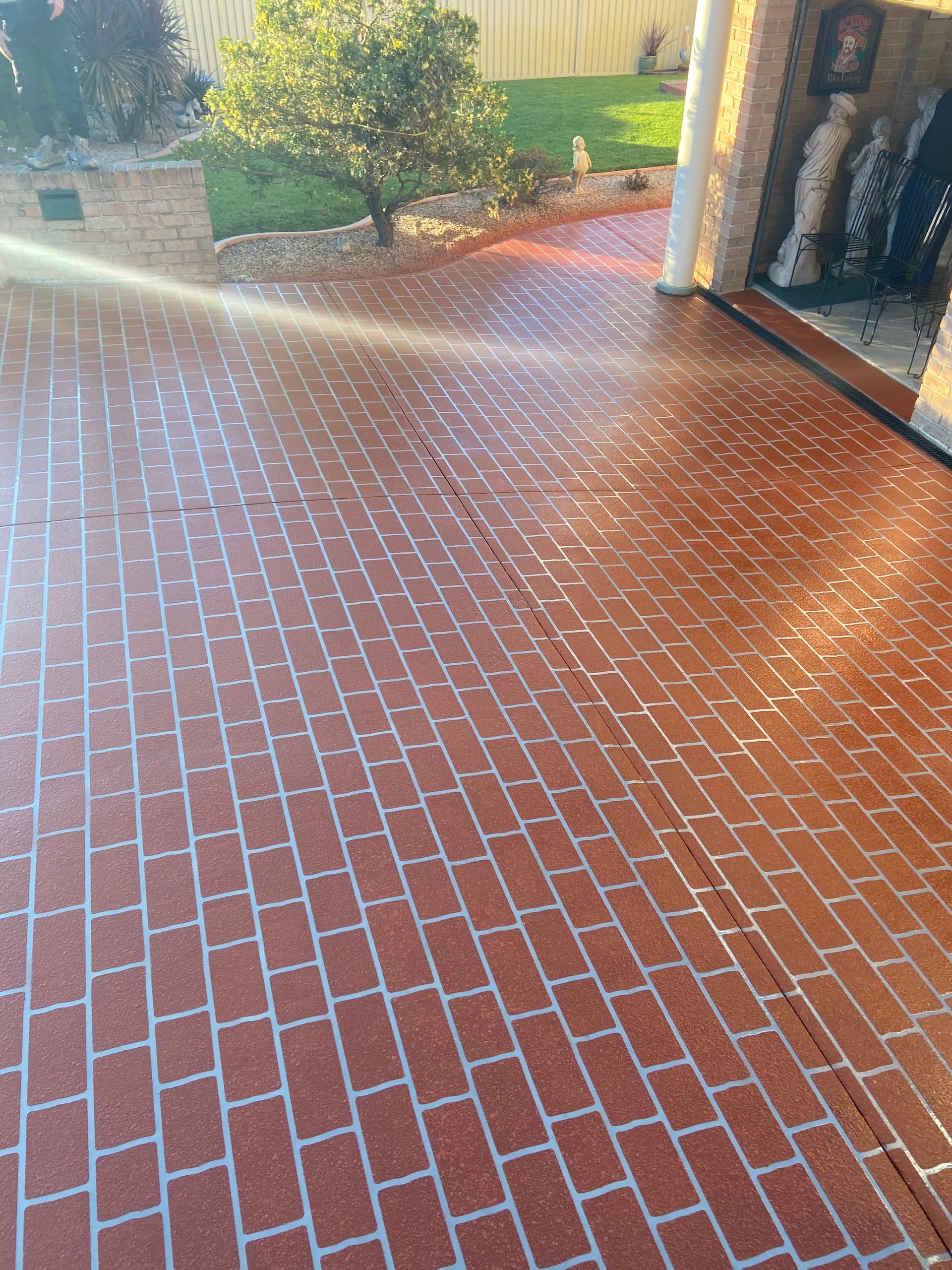 A Man Is Painting a Concrete Surface with A Roller — Illawarra Resurfacing Pty Ltd in Fairy Meadow, NSW