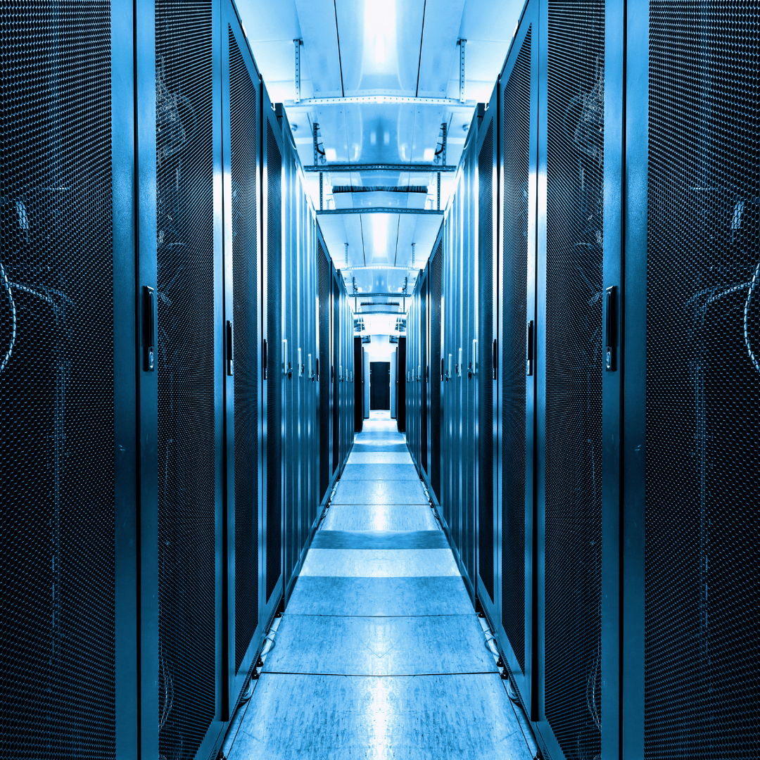 A server room with rows of dark blue servers lining a narrow walkway, brightly lit from above.