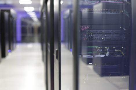 Data center hallway with server racks and blue-lit environment.