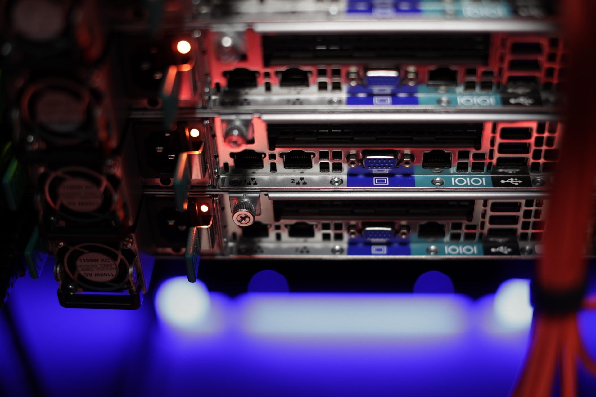 Server rack with multiple circuit boards, blue and red lighting.