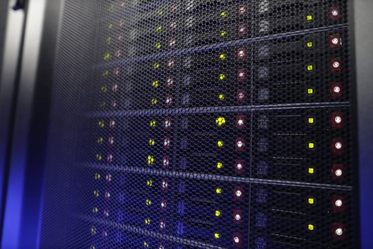 Server rack with multiple blinking lights behind a mesh door.