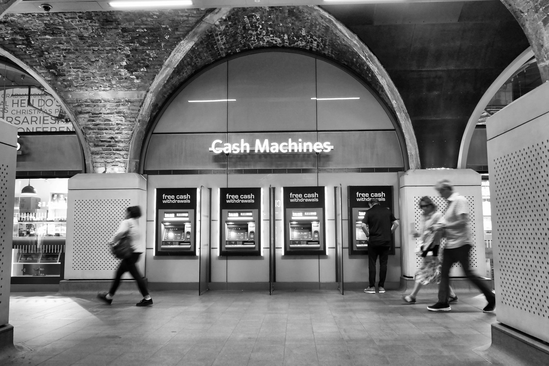 People walk past ATM cash machines in a city or town