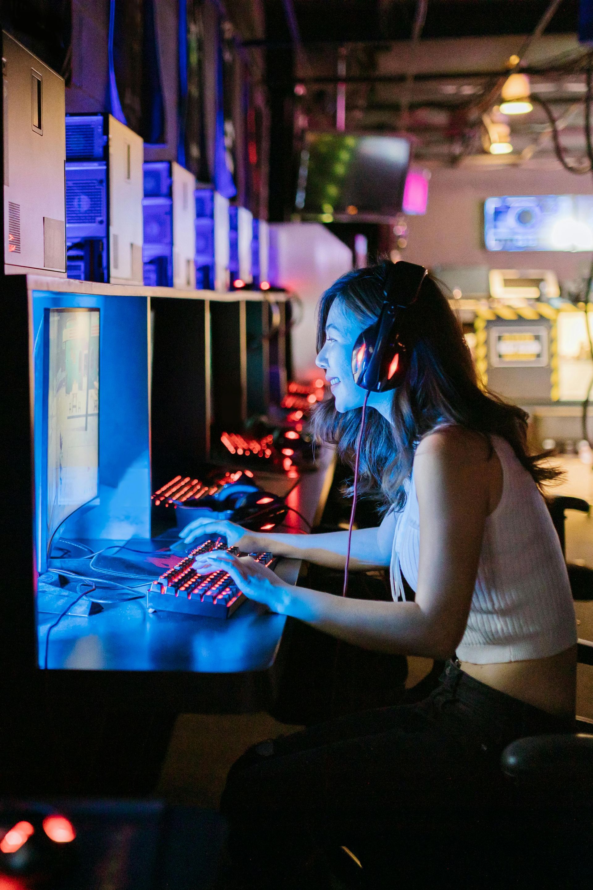 A female gamer is looking at her pc screen and playing a video game.