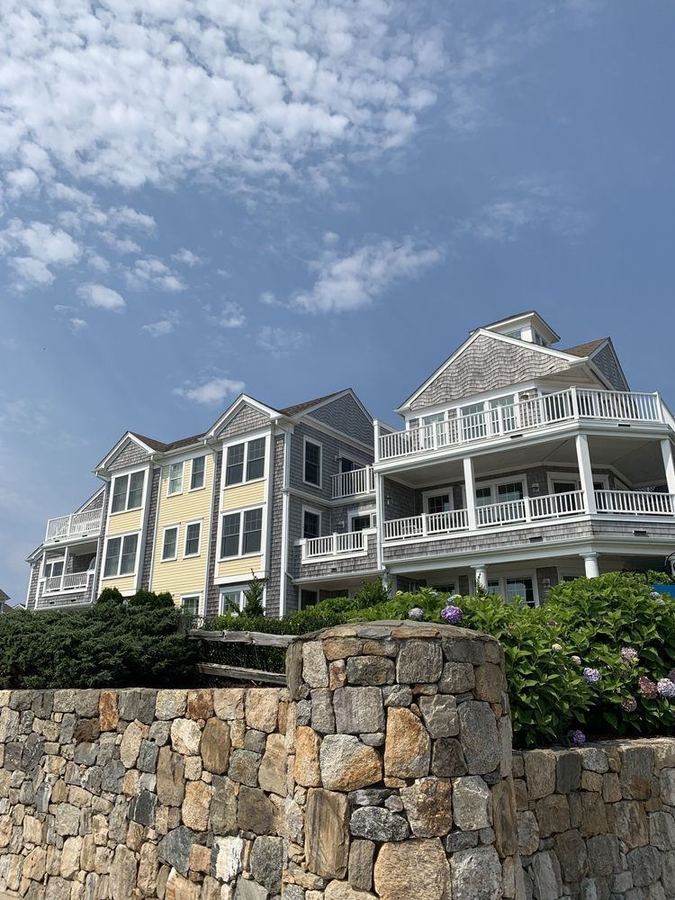 A large house with a stone wall in front of it.