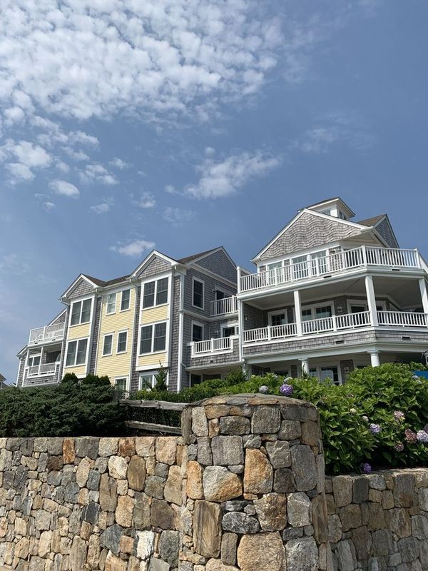 A large house with a stone wall in front of it.