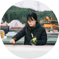Person in a black jacket arranging flowers beside a white railing in an outdoor garden setting