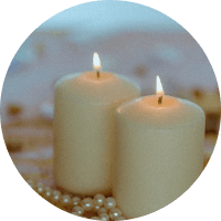 Two lit cream candles beside pearl beads on a soft blurred background