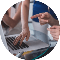 People pointing at a laptop screen during a meeting