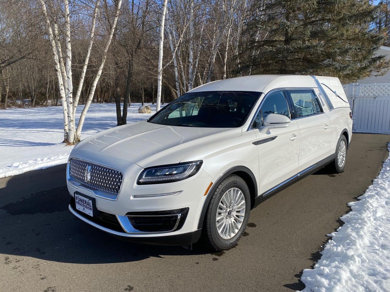 White SUV parked on a snowy road beside birch trees on a winter day
