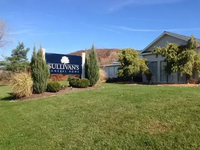 Sullivan's sign in front of a gray building with green lawn and shrubs under a blue sky