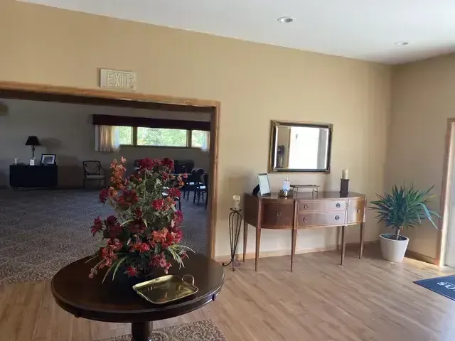 Spacious lobby with tan walls, a round table of flowers, a side table, and potted plants