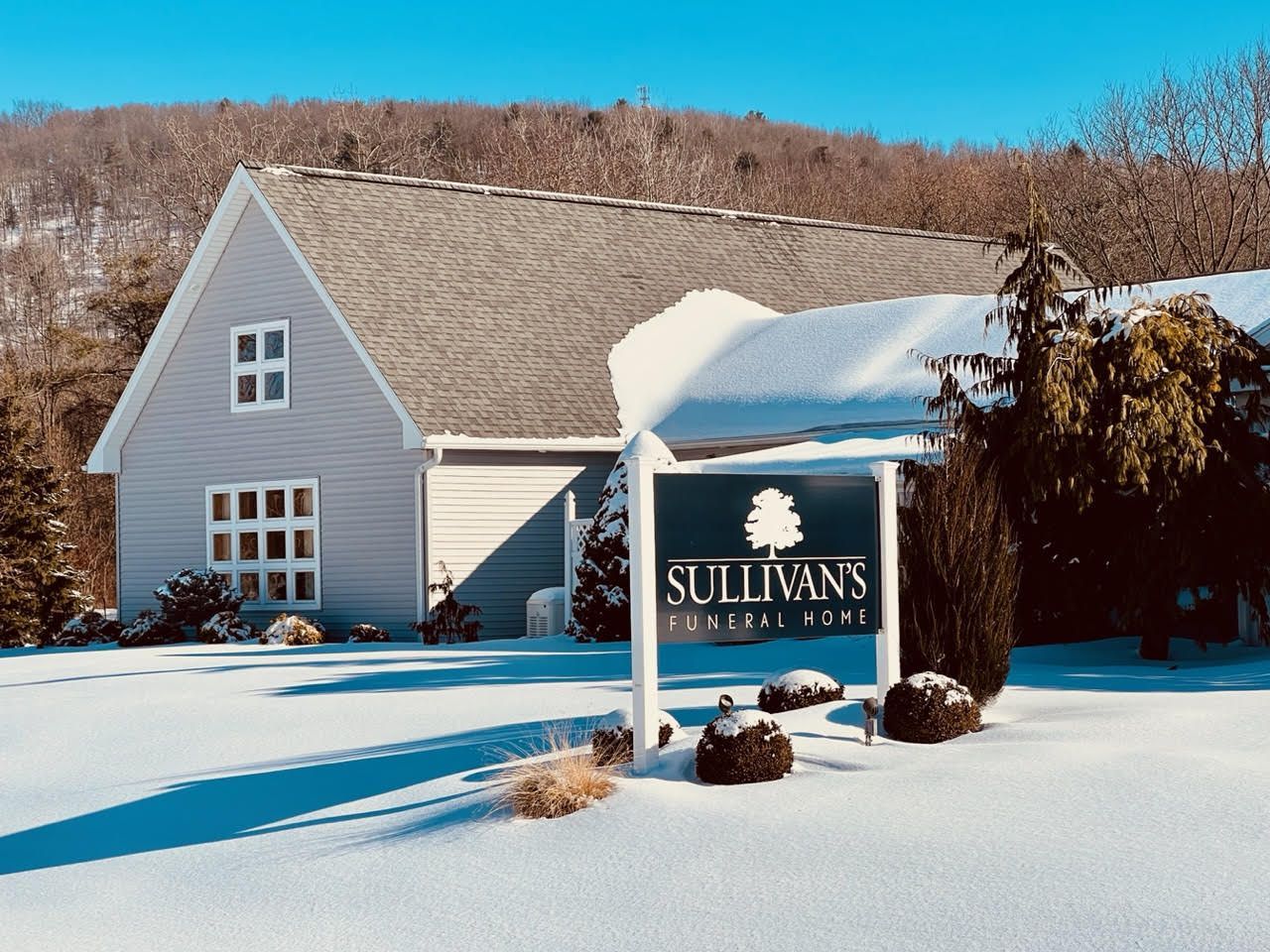 Snowy suburban house with a Sullivans sign in the front yard