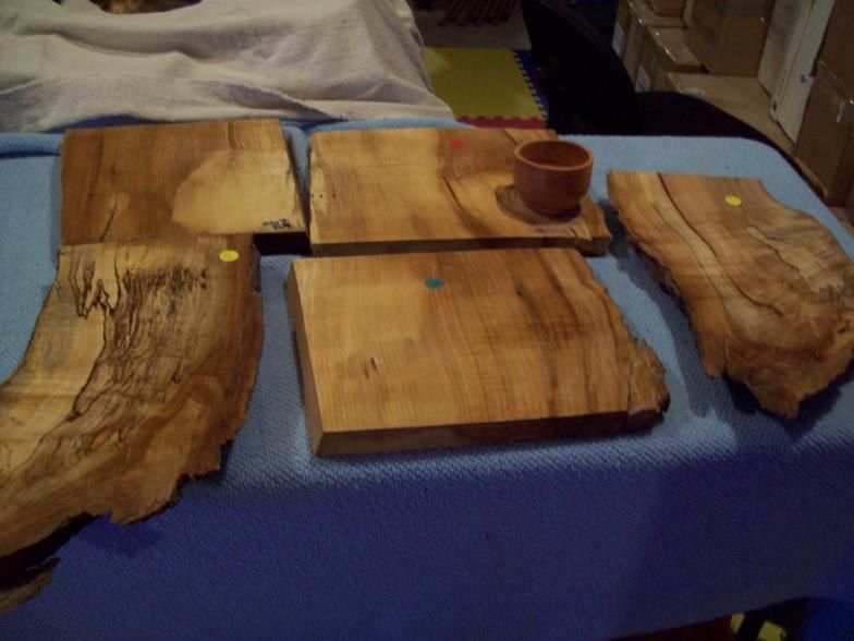 Wooden cutting boards and small bowl on a blue surface, with natural edges and varied wood grain.