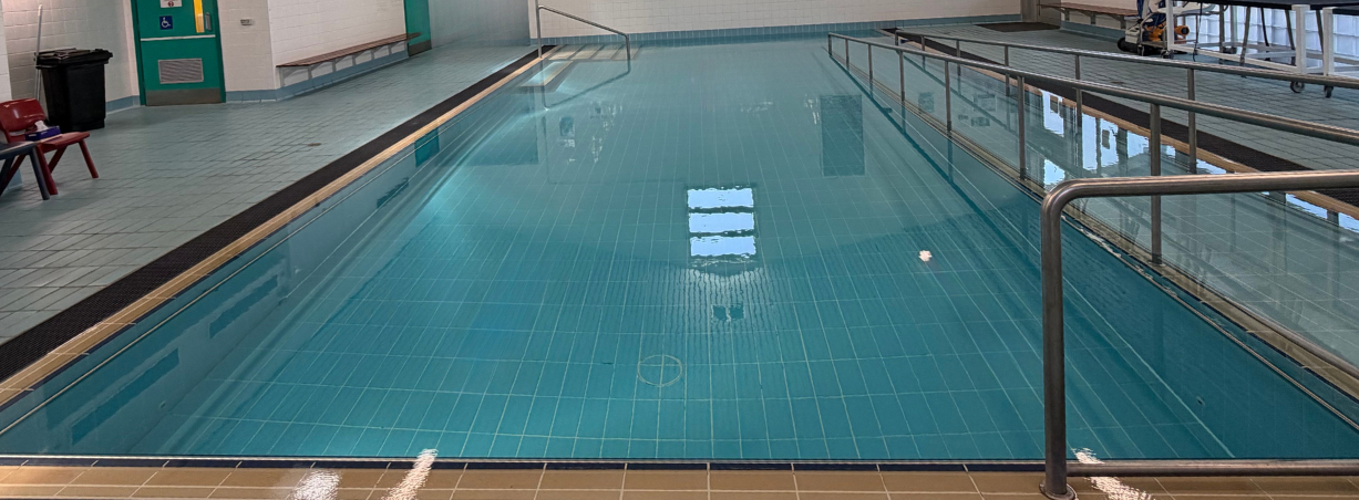 A rectangular swimming pool filled with turquoise water, marked with black lane lines.