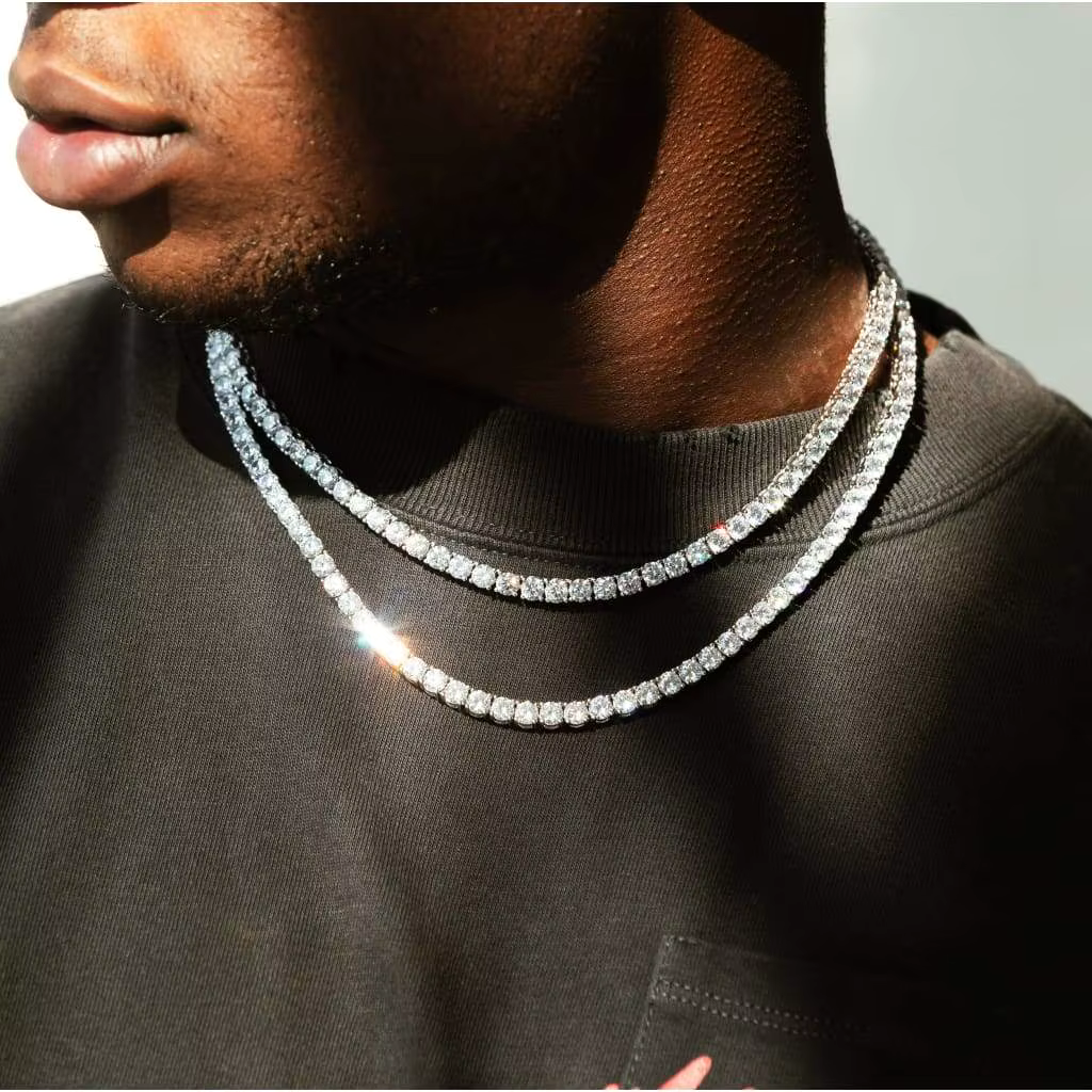 Two diamond chain necklaces over a black shirt against a dark background