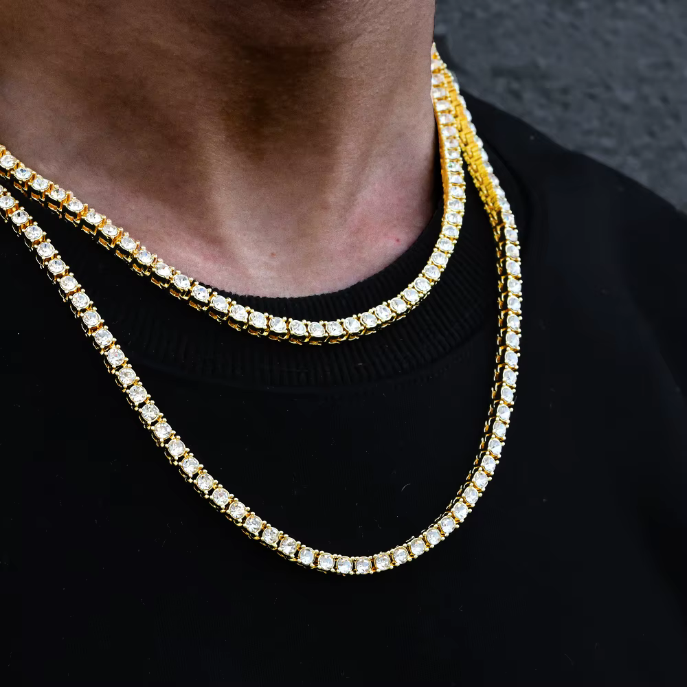 Two diamond chain necklaces over a black shirt against a dark background