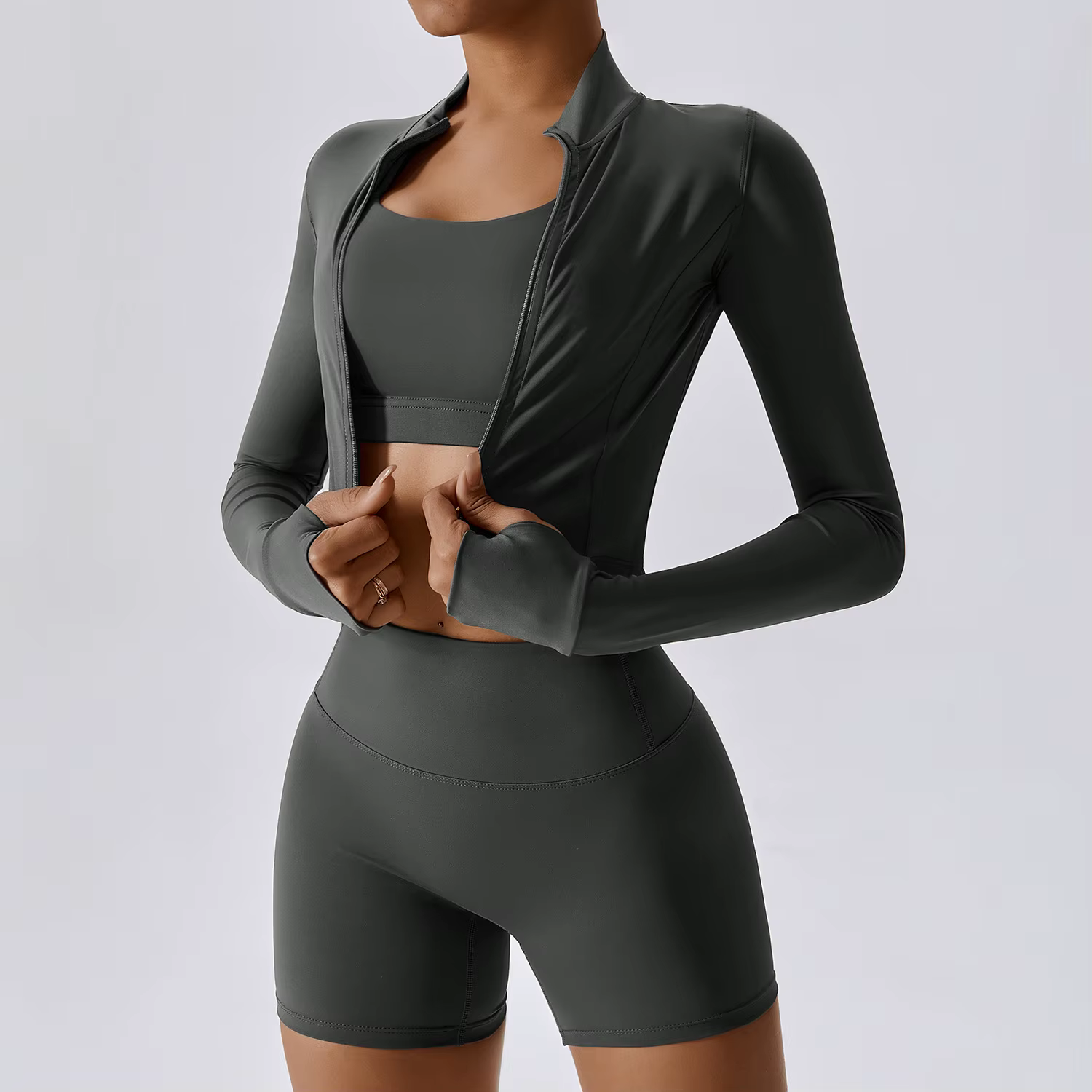 Model in gray activewear adjusting a zip-front jacket on a neutral background