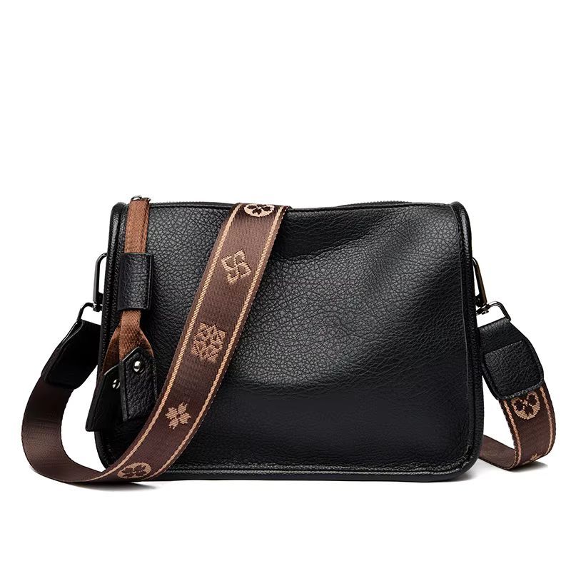 Black leather shoulder bag with brown patterned strap, isolated on white background