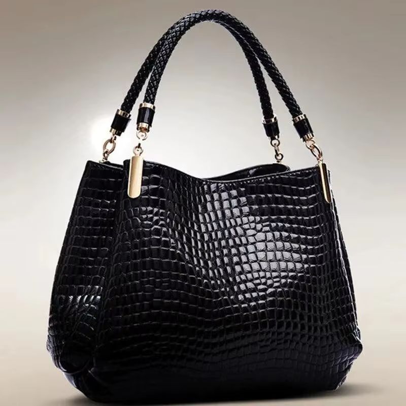 Black crocodile-texture handbag with braided handles and gold hardware on a plain background