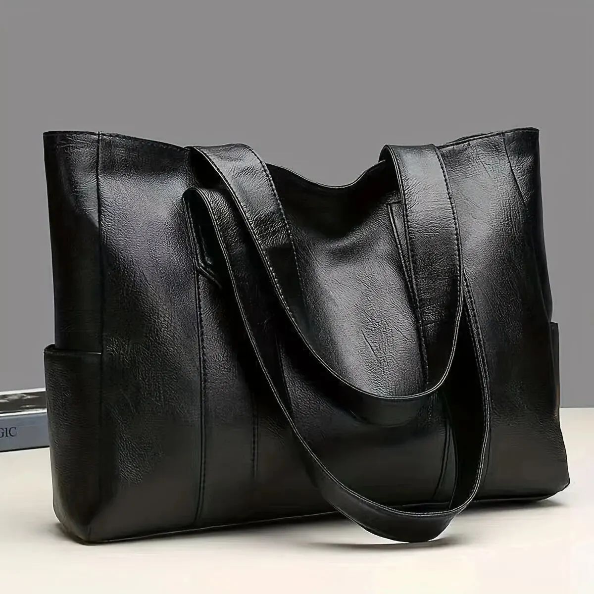 Brown leather tote bag with shoulder straps on a plain background