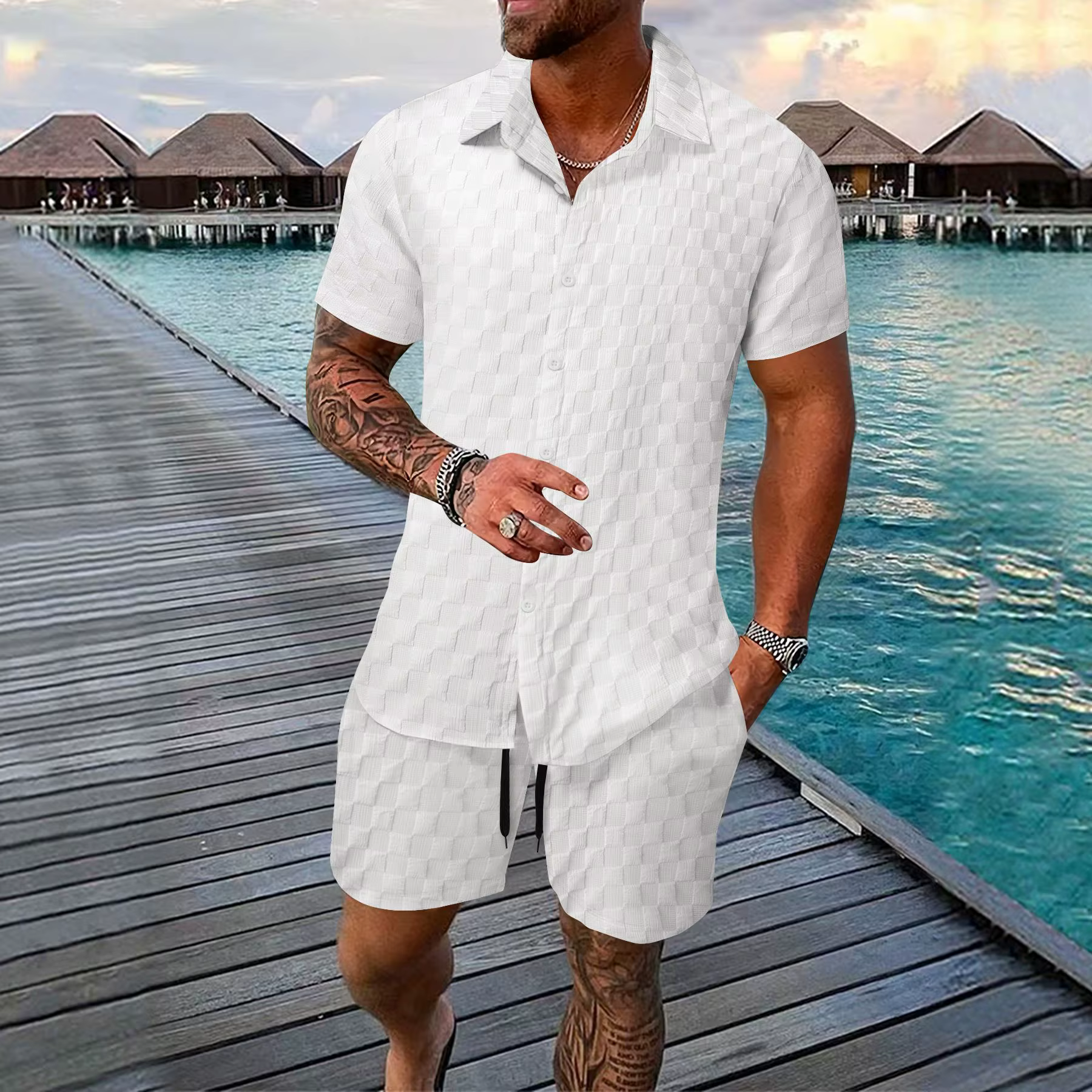 Man in white polo and shorts walking on a boardwalk by overwater bungalows and turquoise water