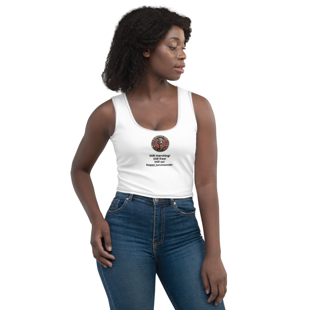 Woman in a white tank top and blue jeans standing against a white background, looking to the side.