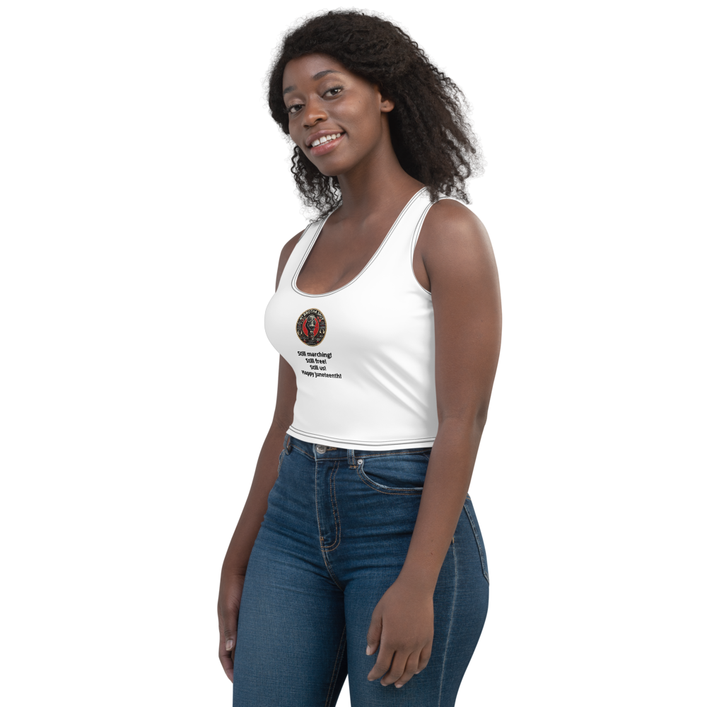 Woman in a white tank top and blue jeans standing against a white background, looking to the side.