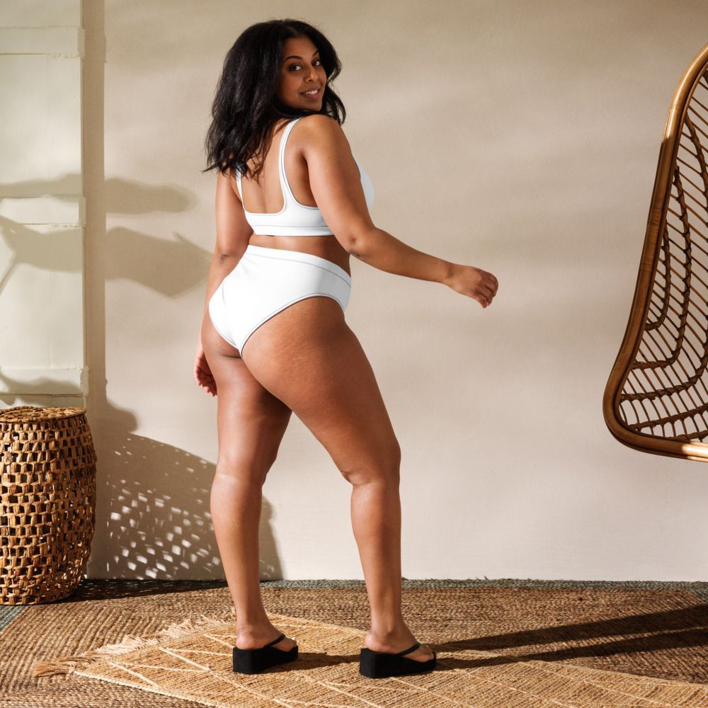 Woman in white athletic wear posing in a sunlit room with woven decor and a rattan chair.