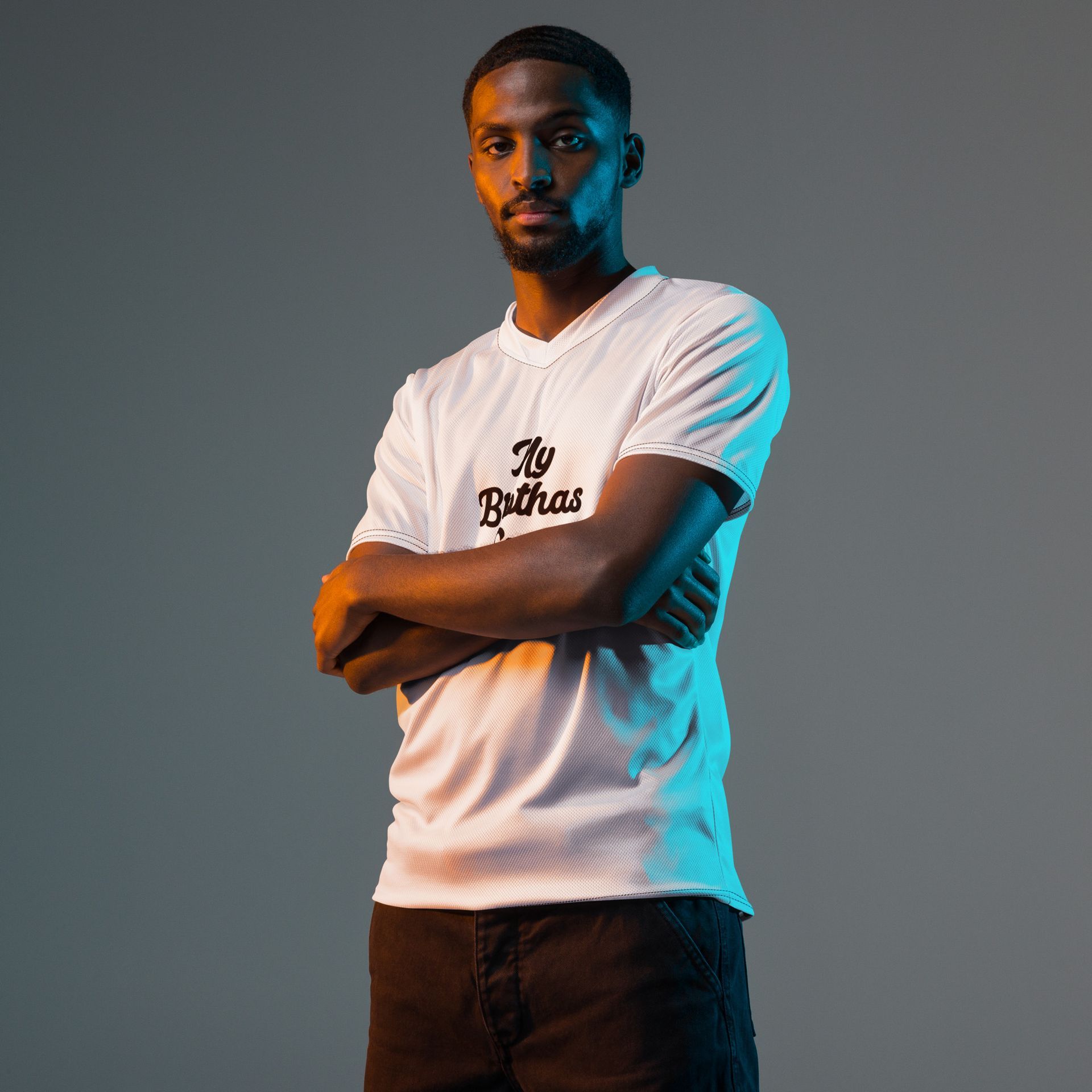 Man in white graphic T-shirt and black pants standing against a white background.