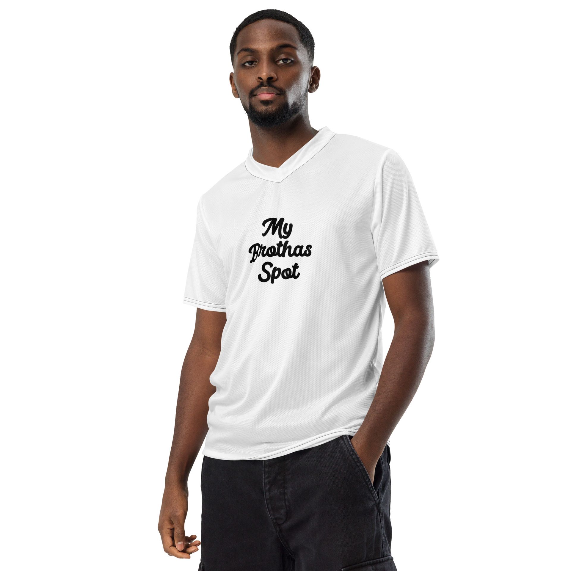 Man in white graphic T-shirt and black pants standing against a white background.