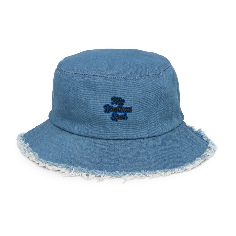 Smiling man in black shirt adjusting a blue bucket hat against a white background