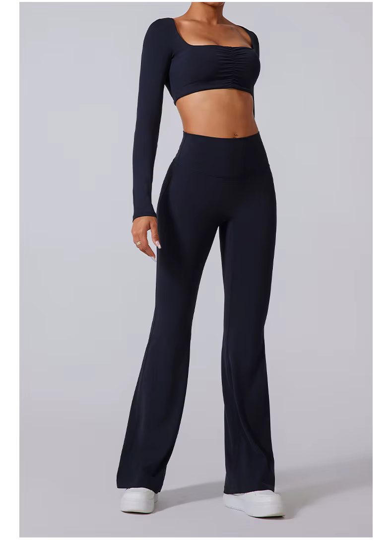 Model wearing black one-shoulder crop top and high-waisted flared pants, standing against a gray backdrop