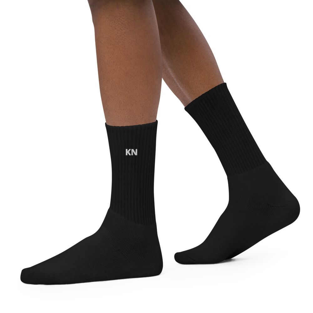 Black socks on a pair of crossed legs, one with a small white “KN” logo.
